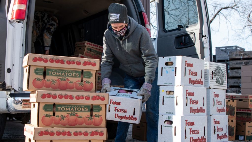 Volunteer loading produce into van for distribution