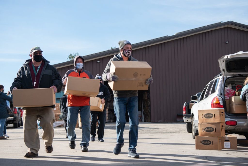 Volunteers carrying boxes of food for distribution