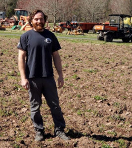 man standing in dirt in field on farm